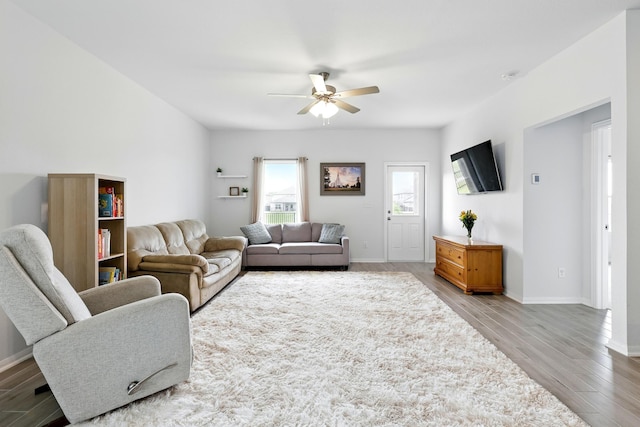 living area featuring a ceiling fan, baseboards, and wood finished floors