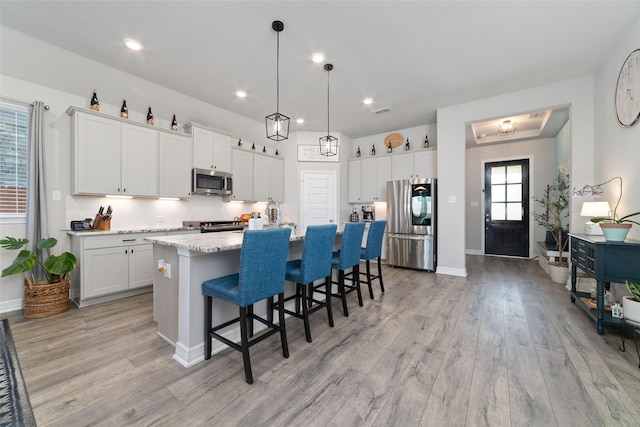 3040 Cirrus Heights Ct, Katy, TX 77493 - kitchen featuring stainless steel appliances, light wood finished floors, a kitchen island with sink, a breakfast bar area, and recessed lighting