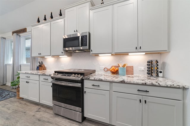 3040 Cirrus Heights Ct, Katy, TX 77493 - kitchen with stainless steel appliances, light wood-type flooring, decorative backsplash, and light stone countertops