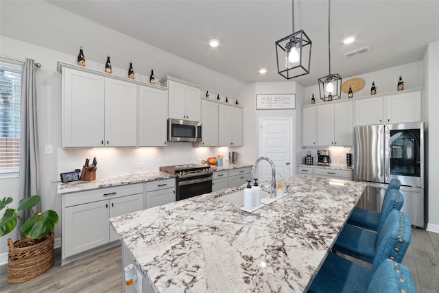 3040 Cirrus Heights Ct, Katy, TX 77493 - kitchen with stainless steel appliances, a sink, light wood finished floors, a kitchen breakfast bar, and recessed lighting
