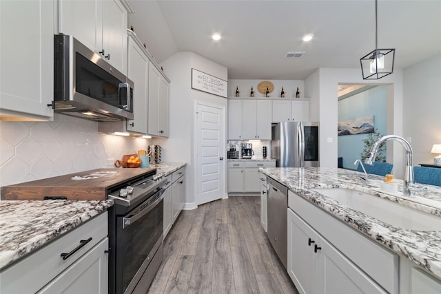 3040 Cirrus Heights Ct, Katy, TX 77493 - kitchen featuring appliances with stainless steel finishes, a sink, wood finished floors, backsplash, and pendant lighting