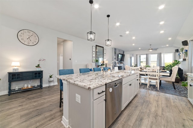 3040 Cirrus Heights Ct, Katy, TX 77493 - kitchen with stainless steel dishwasher, a sink, light wood-style flooring, a kitchen breakfast bar, and ceiling fan