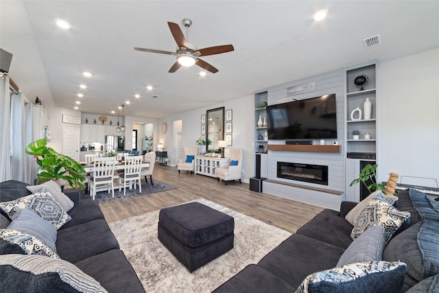 3040 Cirrus Heights Ct, Katy, TX 77493 - living room with a ceiling fan, light wood finished floors, a large fireplace, and recessed lighting