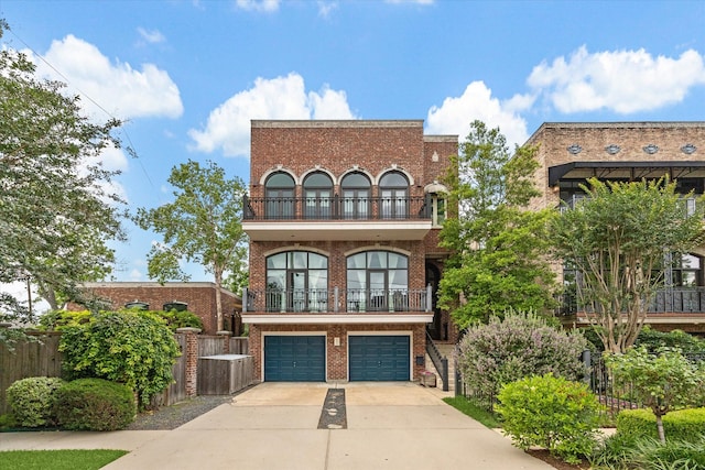 view of front of property with brick siding, an attached garage, a balcony, and driveway
