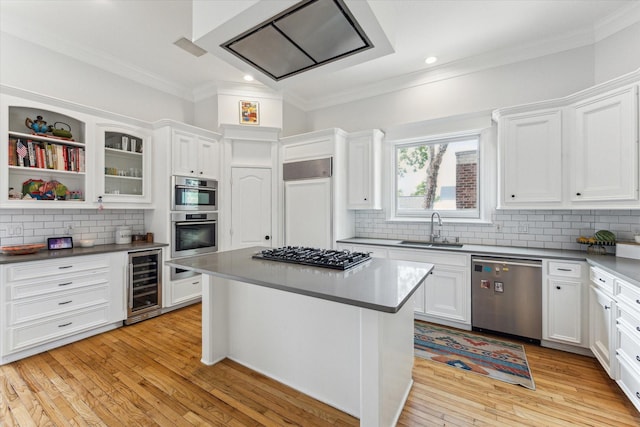 kitchen with a sink, beverage cooler, ornamental molding, stainless steel appliances, and white cabinetry