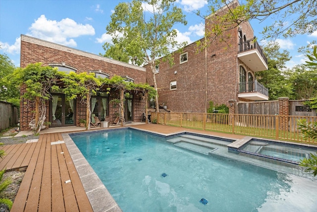 view of pool with a pool with connected hot tub, french doors, a fenced backyard, and a wooden deck