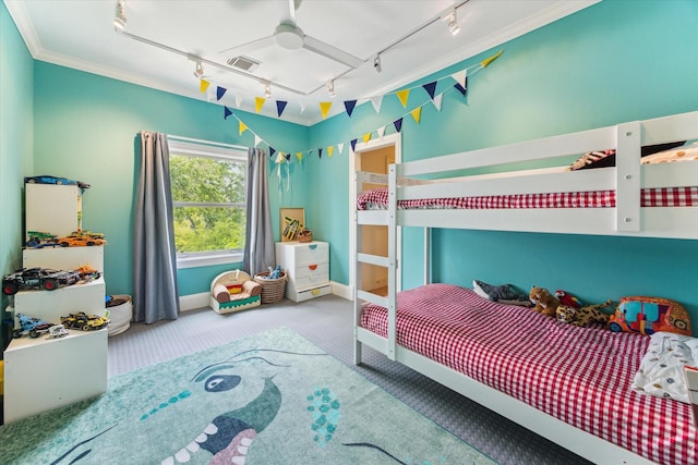 carpeted bedroom with crown molding, track lighting, baseboards, and visible vents