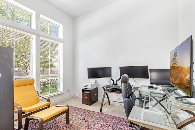 office space featuring baseboards, plenty of natural light, and light carpet