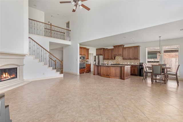 living room with a ceiling fan, a towering ceiling, a high end fireplace, light tile patterned floors, and stairway