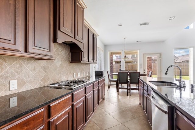kitchen with tasteful backsplash, a sink, light tile patterned floors, hanging light fixtures, and stainless steel appliances