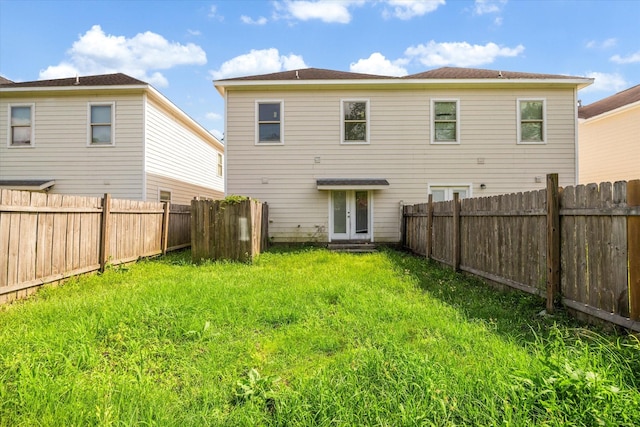 rear view of property with a fenced backyard, a yard, and french doors
