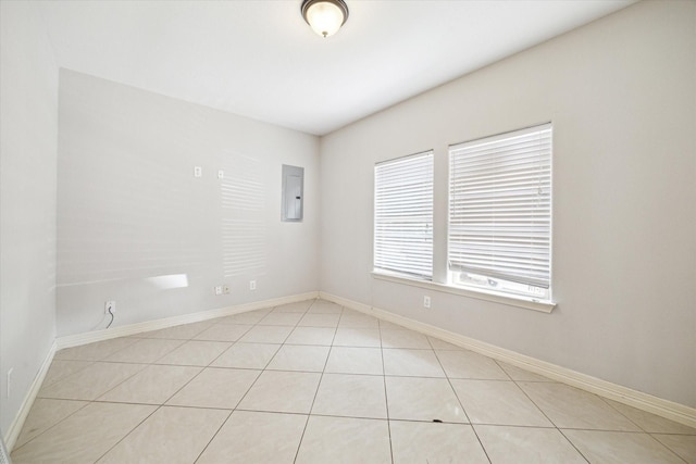 unfurnished room featuring light tile patterned floors, baseboards, and electric panel