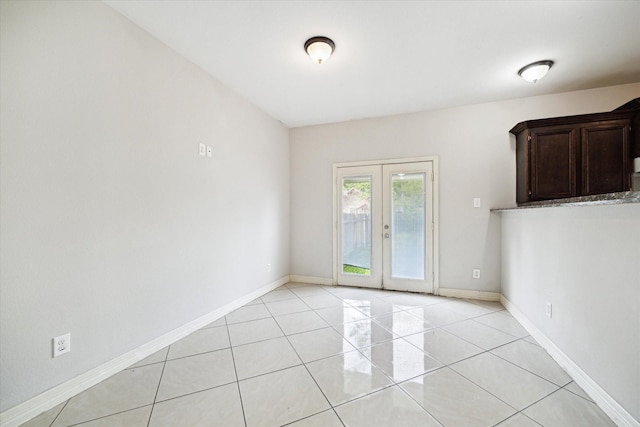 empty room with light tile patterned floors, baseboards, and french doors