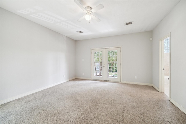 empty room with visible vents, a ceiling fan, and light colored carpet