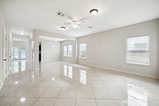 spare room with a healthy amount of sunlight, a ceiling fan, light tile patterned flooring, and visible vents