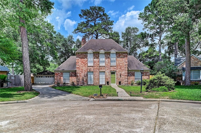 view of front of property featuring brick siding, a front lawn, fence, and a chimney