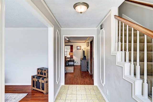 foyer entrance featuring stairs, baseboards, ornamental molding, and wood finished floors