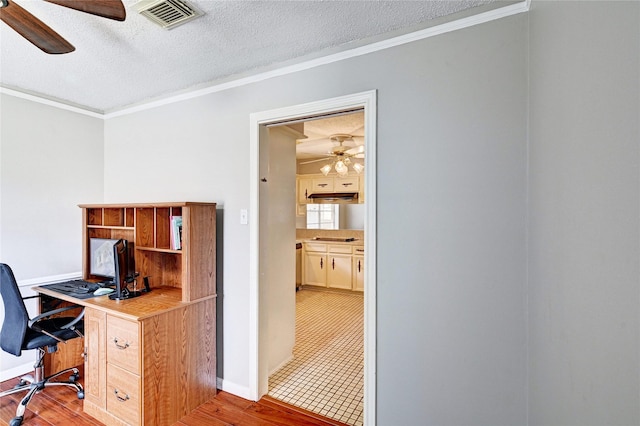 office featuring ceiling fan, ornamental molding, light wood finished floors, and visible vents