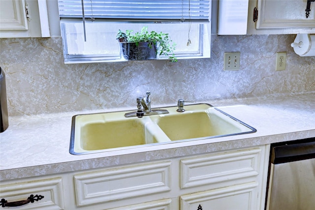 kitchen featuring a sink, decorative backsplash, dishwasher, and light countertops