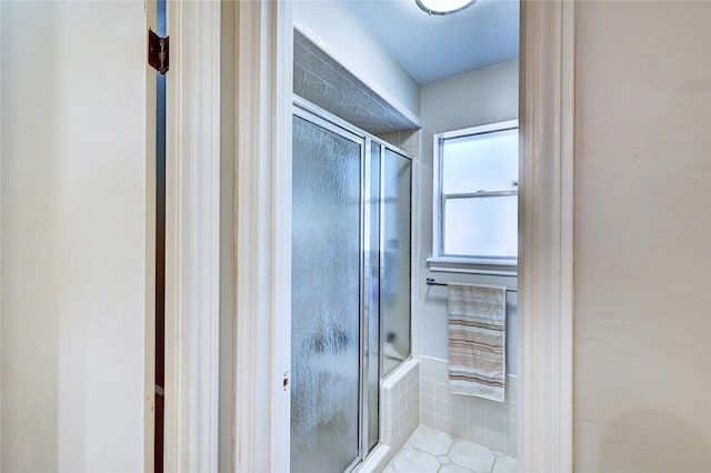 bathroom with a shower with door and tile patterned flooring