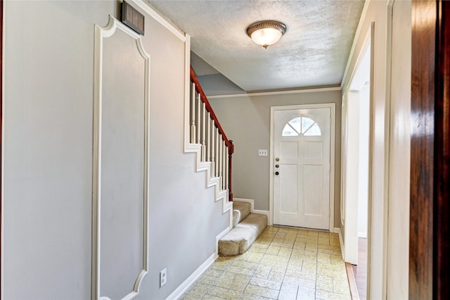 foyer entrance with a textured ceiling, baseboards, stone finish floor, and stairway