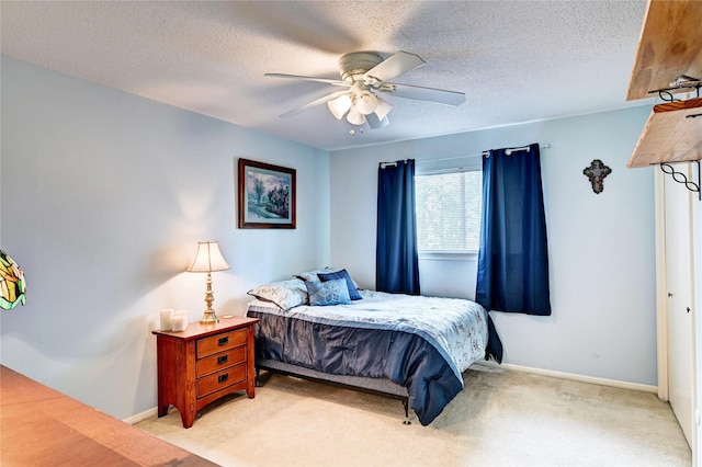 bedroom featuring baseboards, light carpet, a ceiling fan, and a textured ceiling