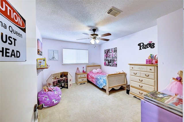carpeted bedroom with visible vents, a textured ceiling, and ceiling fan
