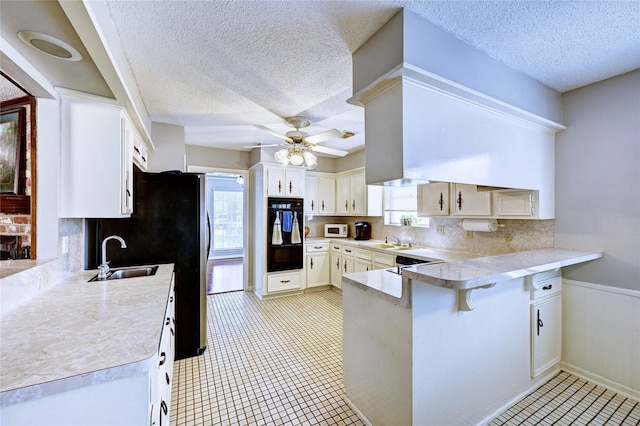 kitchen with a sink, light countertops, a ceiling fan, and a peninsula