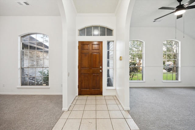 foyer featuring arched walkways, light colored carpet, and visible vents