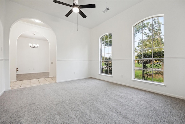 spare room featuring carpet flooring, visible vents, arched walkways, ceiling fan with notable chandelier, and vaulted ceiling