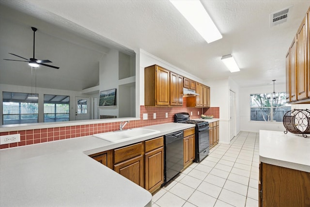 kitchen featuring visible vents, under cabinet range hood, a sink, light tile patterned floors, and black appliances