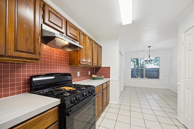 kitchen featuring decorative backsplash, black range with gas stovetop, light countertops, under cabinet range hood, and brown cabinets