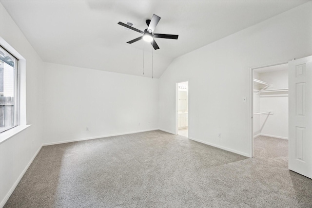 unfurnished bedroom with a spacious closet, baseboards, carpet flooring, and lofted ceiling