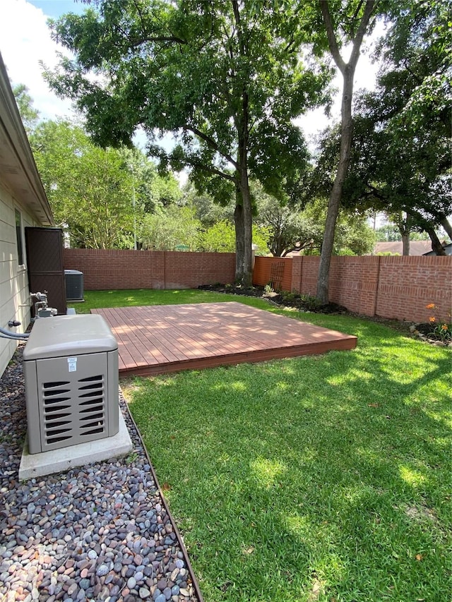 view of yard with a fenced backyard, a wooden deck, and central AC unit