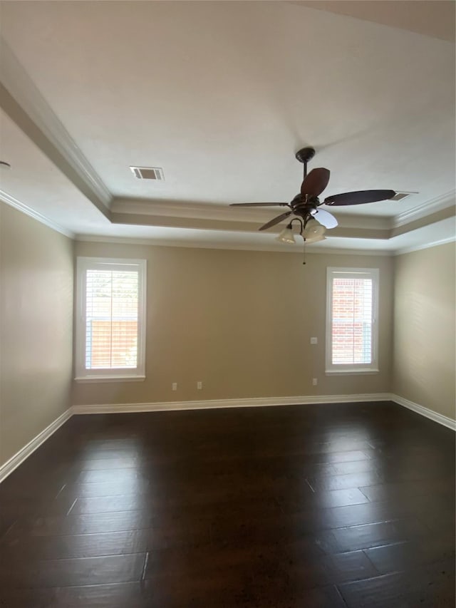spare room with crown molding, a raised ceiling, baseboards, dark wood-type flooring, and visible vents