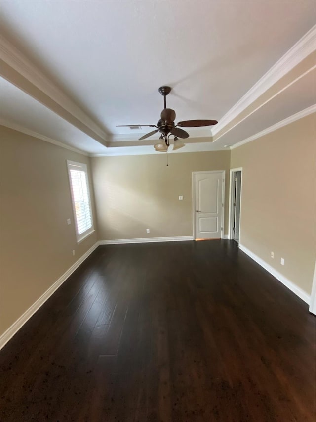 spare room featuring a raised ceiling, baseboards, dark wood finished floors, and ceiling fan