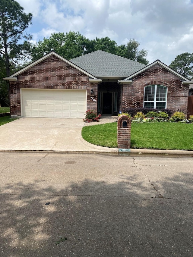 single story home featuring driveway, a front yard, brick siding, an attached garage, and a shingled roof