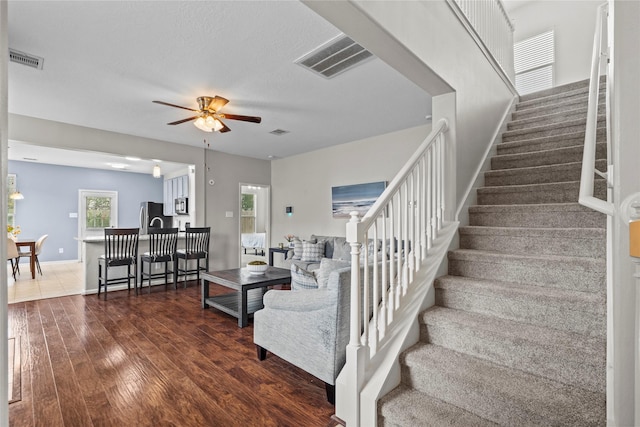 stairs featuring a ceiling fan, baseboards, visible vents, and wood finished floors