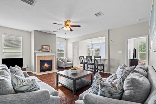 living room featuring a fireplace, a ceiling fan, wood finished floors, and visible vents