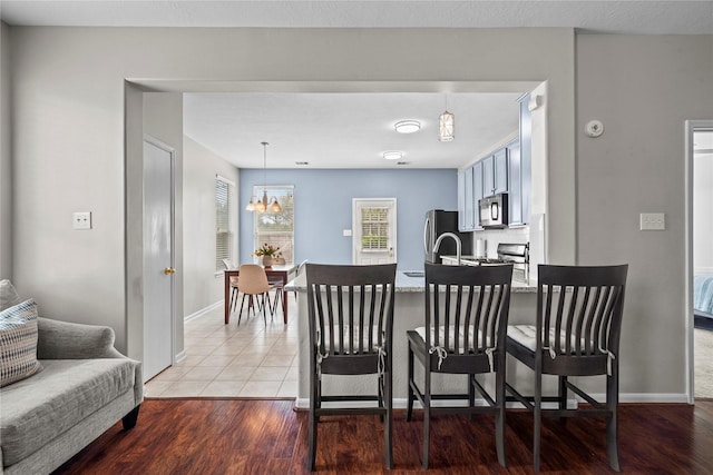 10842 Shannon Mills Ln, Houston, TX 77075 - kitchen featuring an inviting chandelier, a peninsula, wood finished floors, a kitchen bar, and appliances with stainless steel finishes