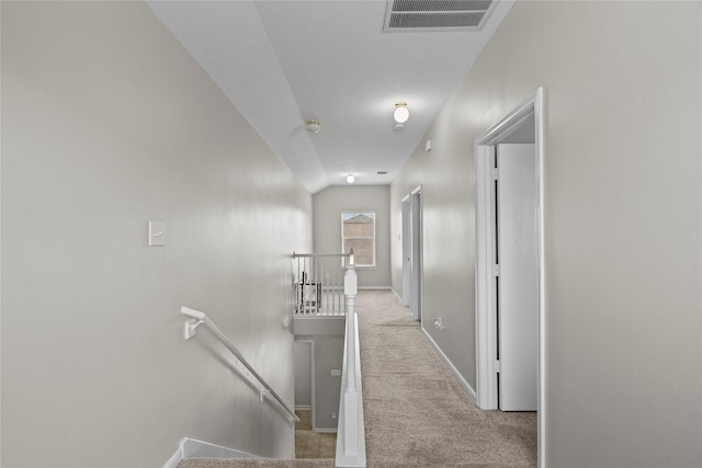 corridor with carpet floors, visible vents, baseboards, and an upstairs landing