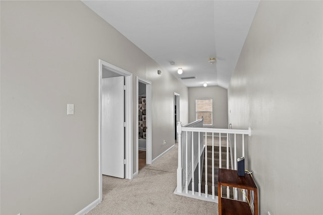 corridor with carpet floors, baseboards, visible vents, and an upstairs landing