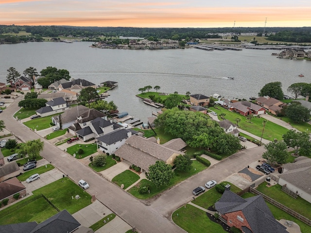 aerial view at dusk featuring a water view and a residential view