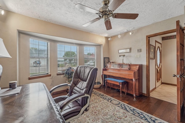 office with rail lighting, ceiling fan, wood finished floors, and a healthy amount of sunlight