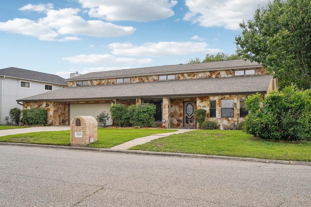 view of front of home featuring a garage, a front lawn, driveway, and stone siding