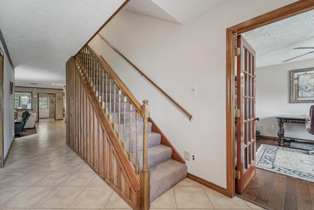 stairs with baseboards, tile patterned flooring, french doors, and a textured ceiling