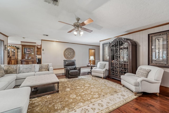 living room with crown molding, ceiling fan, visible vents, and wood finished floors