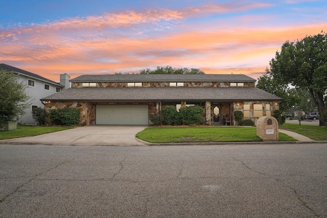 view of front of property with concrete driveway, stone siding, a front yard, and a garage