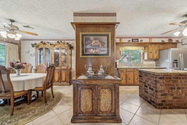 kitchen featuring a textured ceiling, ceiling fan, visible vents, and fridge with ice dispenser