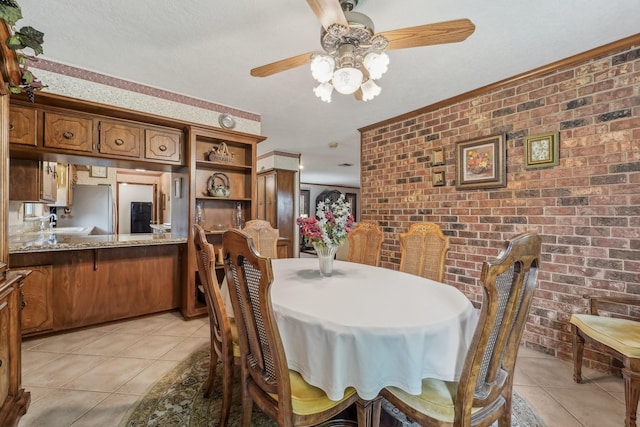 dining space featuring light tile patterned floors, a ceiling fan, and brick wall